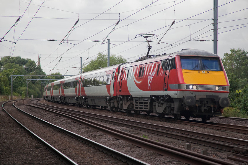 91104, GR 08.30 London Kings Cross-Newcastle (1N08, 1E), Gills Crossing 
 The village of Offord Cluny has two crossings of the ECML. The level crossing is a busy one that causes considerable congestion in the village at certain times. The second is a foot crossing referred to as Gill's Crossing. It's gate controlled with mini colour lights for users to observe. I am sure that it is a crossing that Network Rail have desires to shut along with all the others. Here, the 08.30 King's Cross to Newcastle races past the foot crossing with 91104 leading. 
 Keywords: 91104 1N08 Gills Crossing