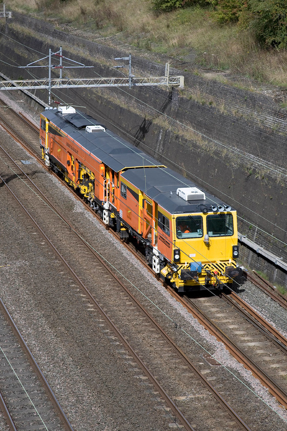 DR73948, 12.00 Nuneaton civil engineers-Euston backing out roads, Roade cutting 
 Looking very smart in its distinctive Colas livery Plasser and Theurer track machine DR73948 passes through Road cutting. It was operating as the 12.00 Nuneaton to Euston and was the first of two such moves in an hour. 
 Keywords: DR73948 12.00 Nuneaton civil engineers-Euston backing out roads Roade cutting Plasser & Theurer Track Machine