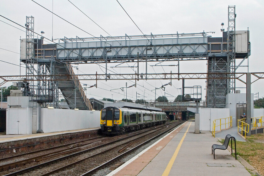 350248, LM 13.14 Birmingham New Street-London Euston, Northampton station 
 340248 wait at Northampton's platform one working the 13.14 Birmingham New Street to London Euston service. It is standing under the huge temporary footbridge that has been constructed whilst the station is redeveloped. It is so tall as it has to safely clear the overhead catenary. Notice the extremely primitive (and very noisy!) lifts at either end of the structure that like the bridge itself, offers no protection to users. That's fine in balmy August but come the autumn and winter it will be a different matter! 
 Keywords: 350248 13.14 Birmingham New Street-London Euston Northampton station