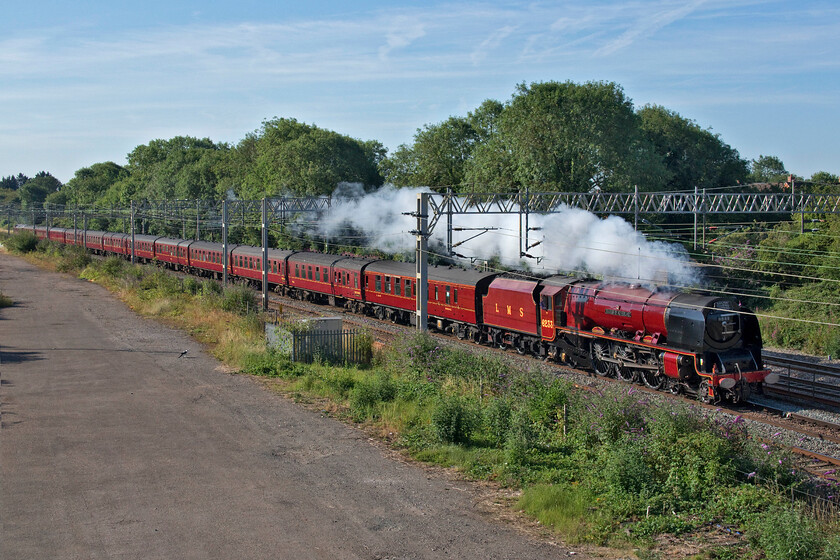 6233, outward leg of The Cheshireman, 06.39 London Euston-Chester (1Z86, 3E), site of Roade station 
 Making a fine sight with its matching set of LMS crimson stock 6233 'Duchess of Sutherland' passes Roade working the outward leg of the Cheshireman charter that left Euston at 06.39 running as 1Z86 heading for, not surprisingly, Chester! Looks can, however, be deceiving with the Duchess not actually doing very much work with just steam emanating from the chimney with 47813 working hard at the rear. With the recent weeks of incredibly dry weather, a steam ban was imminent and it was too risky to have smuts and soot raining down on tinder dry lineside vegetation thanks to a continued lack of maintenance by Network Rail. Notice the inquisitive cat standing stationary watching the train at fairly close quarters seemingly unphased by such a giant noisy machine! 
 Keywords: 6233 The Cheshireman 06.39 London Euston-Chester 1Z86 site of Roade station Duchess of Sutherland