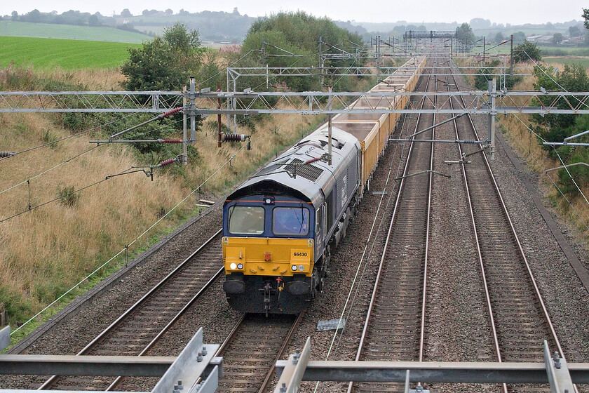 66430, 11.58 Crewe Basford Hall-Cliffe Hill Stud Fm Quarry (6F76, 20E), Hatton Mill bridge SJ822372 
 66430 takes the up slow line past Hatton Mill bridge a remote spot in the Staffordshire countryside between Crewe and Stafford. It is leading the 11.58 Crewe Basford Hall to Cliffe Hill Stud Farm near Coalville in Leicestershire. On arrival, the empty box wagons will be filled with tons of stone that will be used by Network Rail. 
 Keywords: 66430 11.58 Crewe Basford Hall-Cliffe Hill Stud Fm Quarry 6F76 Hatton Mill bridge SJ822372 DRS