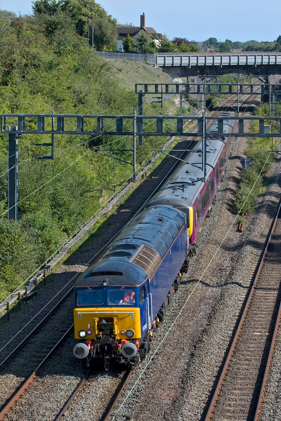 57303 & 360105, 13.08 Kettering Stabling Sidings-Northampton EMD (5B60, 77L), Hyde Road bridge 
 After an unexplained extended layover in Bletchley Carriage Sidings, the 5B60 13.08 Kettering Carriage Sidings to Northamton's Siemens Depot drag is seen passing through Roade from Hyde Road bridge. 360105 is being dragged by 57303 which will be making light work of its task. With Northampton and Kettering just fifteen miles from each other (NE to SW) it seems crazy that the units have to be dragged all the way south and then back north to simply be serviced and have various exams. undertaken - such is the nature of our railway! 
 Keywords: 57303 360105 13.08 Kettering Stabling Sidings-Northampton EMD 5B60 Hyde Road bridge