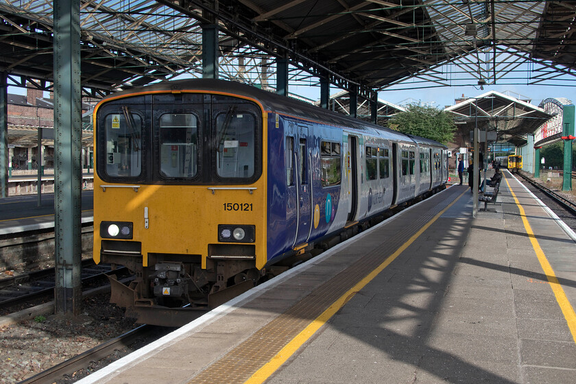 150121, NT 08.02 Chester-Manchester Piccadilly (2H34, RT) & 508124, ME 08.07 Chester-Chester (2C09, 1E), Chester station 
 With the early morning sun creating some interesting shadows created by the roof and ironwork of Chester station's platforms five and six canopy 150121 waits to leave with the 2C09 08.07 Northern service to Manchester Piccadilly. This particular structure at the eastern end of the station was rebuilt in the early 1970s after the catastrophic fire resulting from a crash involving a runaway kerosene train (hauled by Class 24 5028) from Ellesmere Port hitting an empty Class 108 DMU stabled in the adjacent platform to 150121 seen here. 
 Keywords: 150121 08.02 Chester-Manchester Piccadilly 2H34 508124 08.07 Chester-Chester 2C09 Chester station Northern Merseyrail