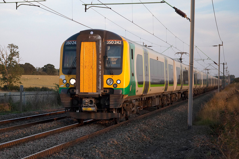 350242, 350244 & 350231, LN 18.21 London Euston-Birmingham New Street (1W25, 6L), Milton Malsor 
 Just catching the final fifteen minutes of sunshine before it disappeared below some trees, 350242, 350244 and 350231 pass Milton Malsor between Roade and Northampton working the 18.21 Euston to Birmingham New Street. This beautifully rural view, complete with grazing sheep, is likely to change beyond belief over the coming couple of years. The land behind the train is earmarked for a huge road/railway interchange along the lines of DIRFT near Rugby. There will be a huge amount of warehousing and a number of loops off the line to the left behind the train. In the field, to my left, there was test drilling taking place so it looks to be somewhat of a fait accompli! 
 Keywords: 350242 350244 350231 18.21 London Euston-Birmingham New Street 1W25 Milton Malsor