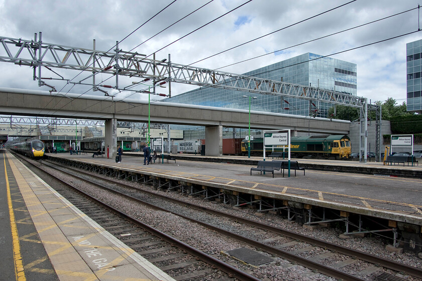 66523, 09.52 Lawley Street-Felixstowe North (4L99, RT) & 390049 VT 06.52 Edinburgh Waverley-London Euston (9M50, 4L), Milton Keynes Central station 
 Milton Keynes (Central?) station is frustratingly tricky for the railway photographer! There is so much station furniture that gets in the way of the subject making composition always a bit of a compromise as is the case here. As 390049 arrives with the 06.52 Edinburgh to Euston Avanti service 66523 heads south at line speed leading the 09.52 Lawley Street to Felixstowe Freightliner. 
 Keywords: 66523 09.52 Lawley Street-Felixstowe North 4L99 390049 06.52 Edinburgh Waverley-London Euston 9M50 Milton Keynes Central station Freightliner Avanti West Coast