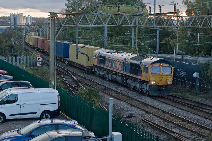 66767, 12.18 London Gateway-Hams Hall (4M47, 1L), Northampton St. James' Road bridge 
 Whilst making our way back from Euston on the rather slow stopper service to Northampton I had been tracking the progress of the 4M57 12.18 London Gateway to Hams Hall service behind us. On arrival, I left my wife at the station whilst I walked the shortish distance to collect the van and within a minute of positioning myself on Northampton's St. James' Road bridge 66767 'King's Cross PSB 1971-1921' appeared slowly around the corner. As can be seen, by the lighting, the sun has begun to set and I really had to ramp up the iso on the camera even to use the relatively slow 1/800th second shutter speed. 66767 appears to have recently been involved in hauling some sort of stone train given the heavy coat of white dust on its bogies and underframe. 
 Keywords: 66767 12.18 London Gateway-Hams Hall 4M47 Northampton St. James' Road bridge GBRf King's Cross PSB 1971-1921