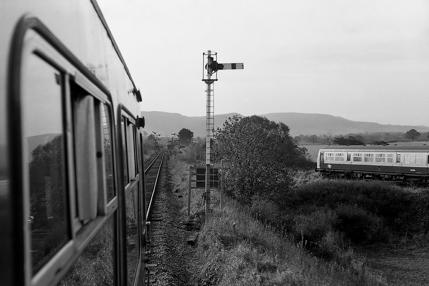 E50293 & E50265, 10.40 Middlesborough-Whitby, from E50248 & E50543, 10.13 Whitby-Midlesboorough, arriving at Battersby 
 A coming together of Class 101 DMUs at Battersby sees the 10.40 Middlesborough to Whitby approaching from the right whilst the 10.13 from Whitby, on which I am travelling heads straight into the station seen in the distance. When two trains arrived on-time at Battersby it gave rise to the rather disconcerting event of them running in parallel to each other for a short distance made even stranger as both had been running on single track for the bulk of their journeys. Notice both home signals pulled off on the twin dolls on the approach to the station. Battersby then and now is a remote station somewhat isolated from the community it professes to serve. The line used to continue on the relatively short distance skirting the northern flank of the North Yorkshire Moors to join the Northallerton to Middlesborough line at Picton. 
 Keywords: E50293 E50265 10.40 Middlesborough-Whitby E50248 E50543 10.13 Whitby-Midlesboorough Battersby Class 101 DMU