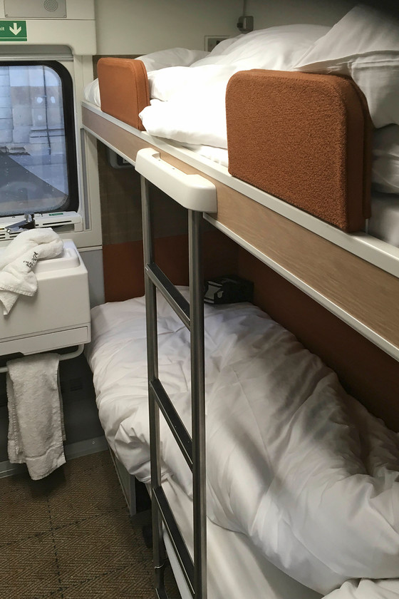 Interior of sleeper compartment, CS 23.36 London Euston-Glasgow Central & Edinburgh Waverley sleeper (via Manchester) (1S26 & 1B26, RT), Edinburgh Waverely station 
 Andy and I shared a twin cabin, what CS call a 'classic room; the new standard'. It was very similar in layout and size to that found on the Mk. III sleepers with better facilities such as USB charging and excellent lighting. There is a small sink but, unfortunately on this particular train there was no hot water. That will have pleased those passengers who paid a hefty premium for en suite showering facilities that gave out luke warm water. Every train was carrying a mobile fitter from CAF but he was unable to fix the problem on this service. Staff were grumbling about having to make constant excuses for the problems being encountered on the services and there was slightly mutinous feel about their mood! However, on the positive, the ride was very good, the beds were very comfortable as were the lovely pillows but some control over the rather 'full-on' air conditioning would have been good; I awoke with a dehydration induced headache! 
 Keywords: Interior of sleeper compartment, CS 23.36 London Euston-Glasgow Central Edinburgh Waverley sleeper 1S26 1B26 Edinburgh Waverely station