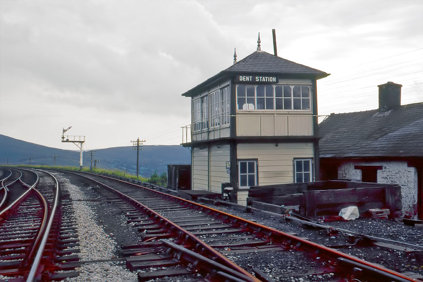 Dent Station Signal Box (MR, 1891) 
 Looking very smart Dent signal box stands just south of the station. The Midland box was built in 1891 and on the day of our visit, it was switched out. It was officially closed some six months after this photograph was taken. It was demolished with the timber burnt on-site during 1984. The low building behind the box is known as the Snow Huts originally built as barracks for construction workers. Today, the buildings have been refurbished and are used for holiday accommodation recently featuring in an episode of the All-4 series Four in a Bed. 
 Keywords: Dent Station Signal Box Midland Railway MR