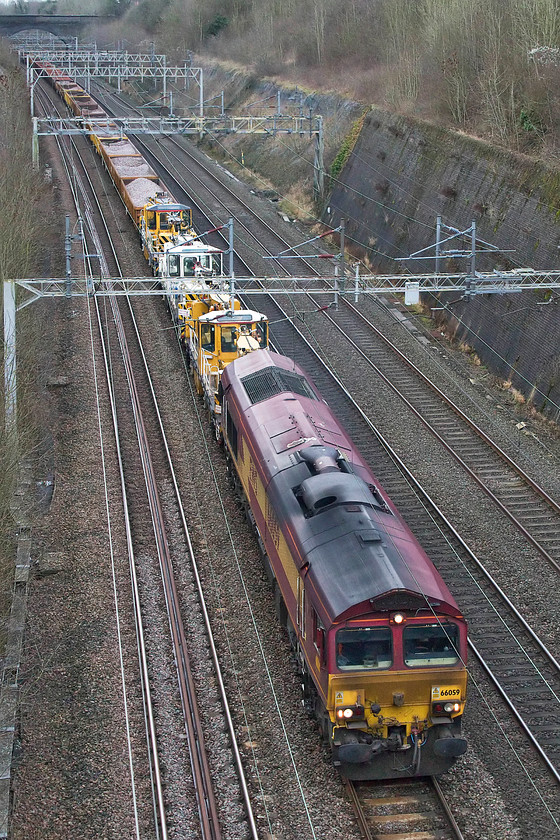 66059, 10.15 Apsley-Crewe Basford Hall, Roade cutting 
 66059 leads the very long and heavy 10.15 Apsley to Crewe Basford Hall infrastructure train. After over-night engineering works, this train first headed south to Wembley on the up slow. On arrival, the 66 ran round and then the train retraced its route continuing north. It is seen passing through Roade Cutting, all 2 200 tons of it, if RTT is to be believed! 
 Keywords: 66059 10.15 Apsley-Crewe Basford Hall Roade cutting