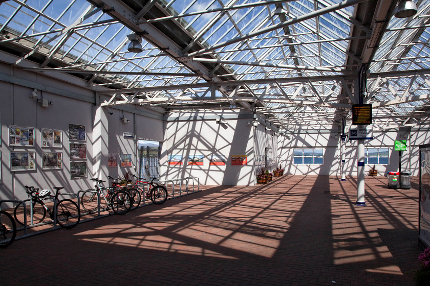 Concourse, Gourock station 
 The wrought iron roof structure is all that remains of the original station at Gourock. When I took a similar picture during a visit in 1984 there were a number of blue Scottish Region enamel signs on the concourse. Whilst the station was run down then, it at least had a platform canopies that it does not have today. 
 Keywords: Concourse, Gourock station