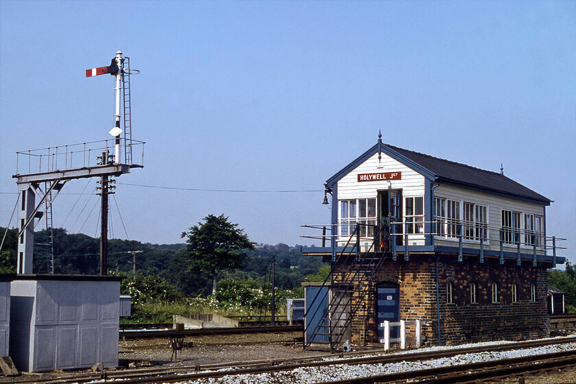 Holywell Junction signal box (LNW, 1902) 
 The fine L&NWR Holywell Junction signal box is seen located between the up and down fast lines. The box is a classic example of an L&NWR Type 5 box that was fitted with a fifty-four lever frame that was considerably reduced over the years as the track was simplified and rationalised. It was reduced further from a quadruple layout to a double track soon after this 1981 photograph was taken. Notice the large bell hanging on the end of the box. This was a feature on a number of the boxes along the North Wales coast used, in times past to warn road traffic that the level crossing gates were about to be closed for an approaching train. 
 Keywords: Holywell Junction signal box LNWR