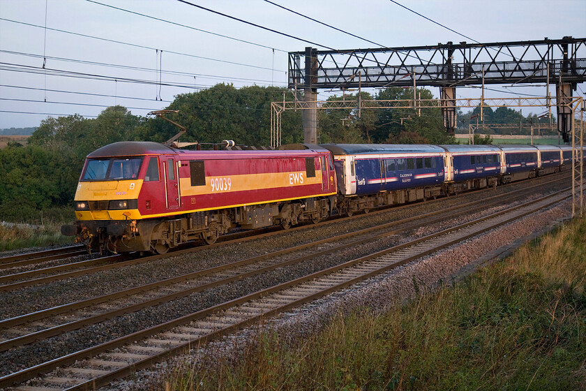 90039, CS 20.44 Inverness, 21.43 Aberdeen & 19.50 Fort William-London Euston sleeper (1M16), Roade Hill, Roade Hill 
 A bit of an identity thing going on here! 90039 is on-hire to Caledonian Sleeper in order to haul the 20.44 Inverness/21.43 Aberdeen/19.50 Fort William to London Euston sleeper. However, the EWS branded and rather tatty looking Class 90 is itself being operated by DB Schenker who acquired EWS back in November 2007. The train is seen passing south near Roade in Northamptonshire with the early morning light just beginning to illuminate the scene so it's shame that I have fluffed the composure partly caused by me teetering on my step ladder trying to avoid the palisade fencing getting in the frame; that's my excuse anyway! 
 Keywords: 90039 20.44 Inverness 21.43 Aberdeen 19.50 Fort William-London Euston sleeper 1M16 Roade Hill Caledonian Sleeper EWS