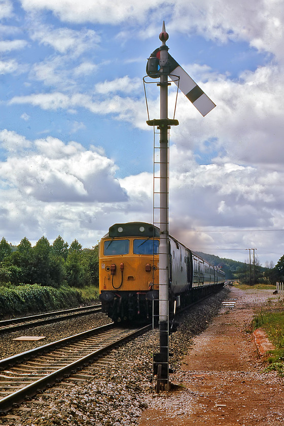 50046, 09.50 Penzance-London Paddington, Hele & Bradninch 
 I did not quite get the positioning right in this photograph but I was using my agricultural Zenith EM camera with all its limitations, not least was its 1:500 /sec. maximum shutter speed. 50046 'Ajax' approaches Hele and Bradninch level crossing with the 09.50 Penzance to Paddington. As can be seen, the sun is out at last, but I am the wrong side for this train, perhaps I was caught out when the gates went down? 
 Keywords: 50046 09.50 Penzance-London Paddington Hele & Bradninch