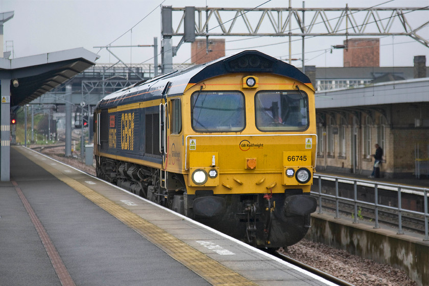 66745, 08.53 Peterborough Maintenance Shed-Hams Hall (0M71), Nuneaton station 
 A photograph that very nearly didn't happen! I was totally unaware that this light engine move was approaching Nuneaton until the automated announcement came over the tannoy advising passengers that the next train was not stopping, as I turned around it was approaching the end of the platform. Luckily, the camera settings were sufficient to capture 66745 'Modern Railways The First 50 Years' passing as the 0M71 08.53 Peterborough depot to Hams Hall. I suspect that the Class 66 had been undergoing maintenance or an exam. at the GBRf facility and that it was now making its way to Birmingham in order to undertake its next job. 
 Keywords: 66745 08.53 Peterborough Maintenance Shed-Hams Hall 0M71 Nuneaton station GBRf GB Railfreight Modern Railways The First 50 Years