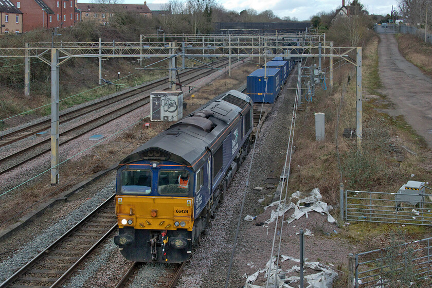 66424, 13.51 DIRFT-Ripple Lane (4L48, 1E), site of Roade station 
 The 4L48 is one of the most dependable and long-running freights on the southern section of the WCML. It leaves Daventry at lunchtime, in this case, 13.51, and is operated by DRS going to Ripple Lane and then on to the Purfleet deep water port. It is seen here passing the site of Roade station, with the sun having gone back in, led by 66424. 
 Keywords: 66424 13.51 DIRFT-Ripple Lane 4L48 site of Roade station DRS Direct Rail Services