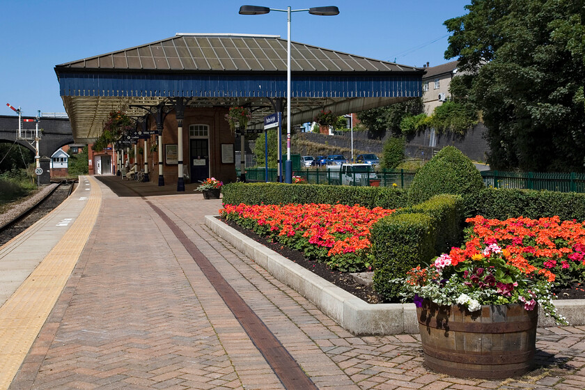 Poulton-le-Fylde station 
 What a lovely sight Poulton-le-Fylde station is! Complete with a superb twin doll bracket signal in the background, the platforms are a riot of colour thanks to the friends of the station. Also, notice the hanging baskets that run the length of the awnings. I cannot help but feel that when the electrification masts and wires arrive at Poulton station in the coming few years the atmosphere of the station will be spoilt somewhat. 
 Keywords: Poulton-le-Fylde station