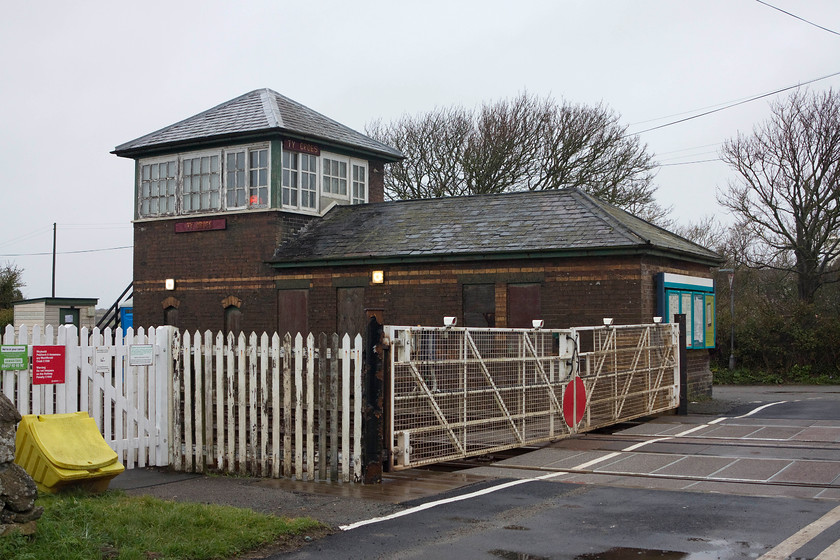 Ty-Croes Signal Box (LNWR, 1892) & level crossing 
 The unusual Ty-Croes signal box with its integrated lineman's accommodation is seen with the manually operated level crossing gates. Built by the LNWR in 1892, the box is largely unmolested retaining its unusual pyramidal slate roof. The signalman has a fair trek to operate the gates going from the box steps around the back of the building to the road. I hope that suitable foul weather clothing is provided by Network Rail for use as in the winter I should imagine that this is a pretty rough place to work! 
 Keywords: Ty-Croes Signal Box level crossing