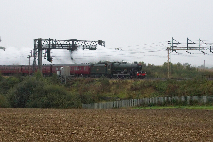 45596, outward leg of The Mancunian, 07.12 London Euston-Manchester Piccadilly (1Z96, 5E), between Roade & Ashton 
 With an up Freightliner having just got out of the way Jubilee 45596 'Bahamas' emerges from a shallow cutting near the Northamptonshire village of Ashton. Hauling the outward leg of The Mancunian charter 45596 left Euston at 07.12 arriving at Manchester Piccadilly slightly ahead of time. It is unfortunate that the weather is so dull and misty as Bahamas does not really lift itself from the background wearing its British Railways green livery. 
 Keywords: 45596 The Mancunian 07.12 London Euston-Manchester Piccadilly 1Z96 between Roade & Ashton