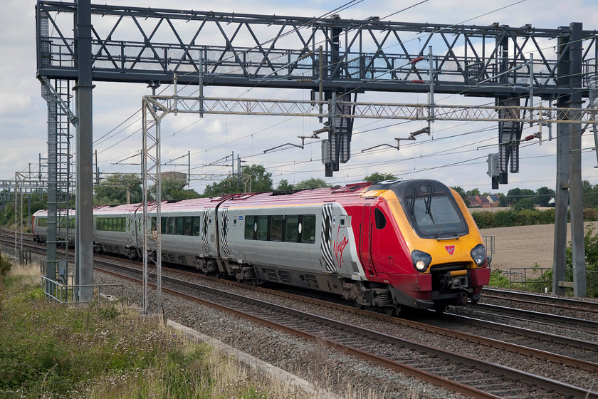 221142, VT 12.17 Preston (11.58 Lancaster)-London Euston (9A53, 7L), Ashton Hill 
 221142 'Bombardier Voyager ' heads south at Ashton Hill between Roade and Wolverton working the 9A53 11.58 Lancaster to London Euston. Why path a glorified DMU on this turn that will travel the entire distance of 229 miles using diesel power under electrified lines? 
 Keywords: 221142 9A53 Ashton Hill