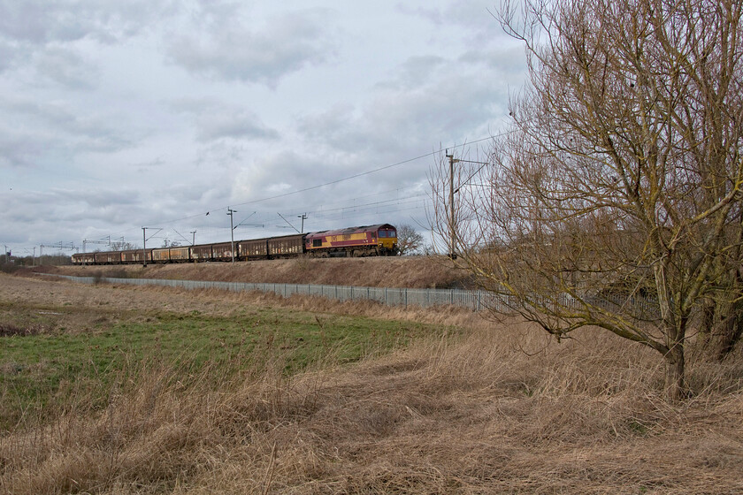 66199, 14.47 DIRFT-Dollands Moor (6M45, 1E), Kingsthorpe SP737635 
 In line with other Freightliner and intermodal trains, the daily 6M45 empty Ferrywaggon train from Daventry to Dollands Moor is also operating at a much-reduced capacity. This train is usually very long and makes a right racket due to the resonance of the empty wagons when compared to its balancing loaded service. 66199 leads the train on the approach to Northampton passing Kingsthorpe. The land to the left is under threat of development to become a huge housing area, at least this is the plan following lengthy and protracted discussions over the last few years. So much so that the soil in the field has not been cultivated for a number of seasons now in anticipation of the work commencing! 
 Keywords: 66199 14.47 DIRFT-Dollands Moor 6M45 Kingsthorpe SP737635 EWS bottled water train