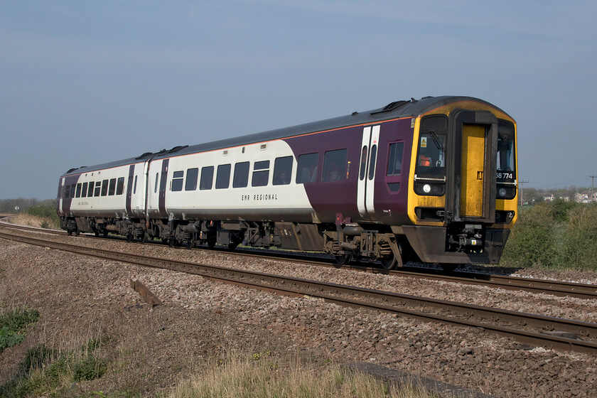 158774, EM 09.39 Nottingham-Norwich (1L06, 1L), Harts Drove crossing TL273962 
 The revised purple and white livery that has been applied to some of East Midlands' stock looks very smart and brings another refresh to the Class 158s that are now getting on a bit approaching their twenty-fifth year! 158774 approaches Whittlesey working the 09.39 Nottingham to Norwich train. 
 Keywords: 158774 09.39 Nottingham-Norwich 1L06 Harts Drove crossing TL273962