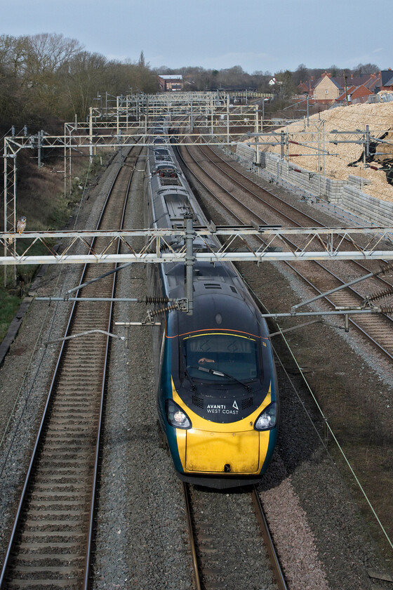 390112, VT 09.15 Manchester Piccadilly-London Euston (1A19, 4L), Ashton Road bridge 
 390112 speeds southwards towards London working Avanti West Coast's 09.15 Manchester to Euston train. It is about to pass under Ashton Road bridge with the village of Roade in the background along with the almost complete embankment stabilisation work to the right. Notice the bird of prey, that I believe to be a kestrel, standing on the gantry cross piece appearing to be totally unphased by the passage of the train just a few feet from where it is perched! 
 Keywords: 390112 09.15 Manchester Piccadilly-London Euston 1A19 Ashton Road bridge Avanti West Coast Pendolino