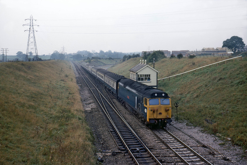 50001, 07.50 Paignton-London Paddington (1A07), Clink Road Junction 
 No doubt the interior of the Type 28B Clink Road Junction signal box will be rattling as 50001 'Dreadnought' passes at line speed leading the 07.50 Paignton to Paddington express. The box was opened relatively late in 1933 when the Frome avoiding line (or cut off as we colloquially referred to it) was constructed. The Frome line can be seen to the rear of the train, curving off to the right which had, by this stage, been singled. Some thirty-five years later, the scene is virtually unrecognisable thanks to total lack of management of the lineside environment. The only thing still to provide any reference is the railings leading down to the signal box and the high tension wire pylons, see...... https://www.ontheupfast.com/v/photos/21936chg/28469035804/x59203-11-35-merehead-quarry-wootton 
 Keywords: 50001 07.50 Paignton-London Paddington 1A07 Clink Road Junction