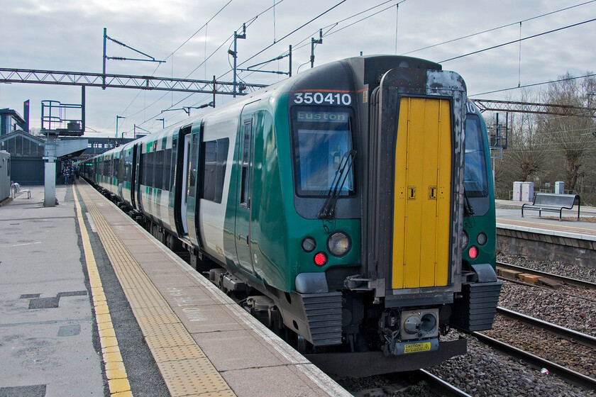 350410, LN 09.06 Birmingham New Street-London Euston (1Y18, RT), Northampton station 
 Our train to London from Northampton sits at the platform ready to depart. We travelled aboard 350410 at the rear of the 09.06 Birmingham to London service. It was already extremely full when it arrived in from the Midlands with a significant number of passengers waiting to board. The train was full and standing all the way with the guard apologising profusely for the situation. He suggested that we log on to the WMT app. and outline how busy the train was. He handled the situation very well and, needless to say, did not carry out a ticket check! 
 Keywords: 350410 09.06 Birmingham New Street-London Euston 1Y18 Northampton station