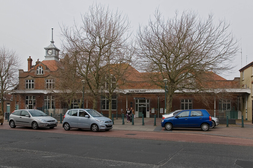 Frontage, Bognor Regis station 
 The superb Edwardian frontage of Bognor Regis station is partially hidden by some trees but these cannot disguise its grandeur. It dates from 1902 replacing the original 1864 structure that burned down in a fire. The building is Grade II listed by Historic England summarising it in their citation as being 'a complete example of the seaside terminus station of the Edwardian period'. 
 Keywords: Frontage, Bognor Regis station