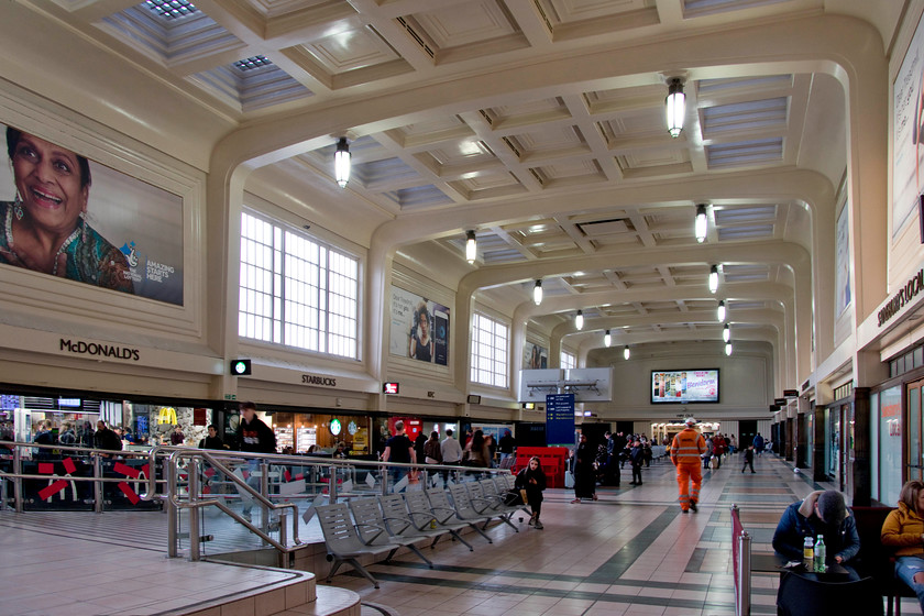 Concourse, Leeds station 
 William Henry Hamlyn's 1938 designed station concourse at Leeds has an almost continental look about it. It's a magnificent space that leads to the modern concourse opened in 2008 that itself is having yet another re-build! The retail outlets to the left of this image were once the access to the terminating platforms. Note the new lighting fitted inside the old style art deco fittings.