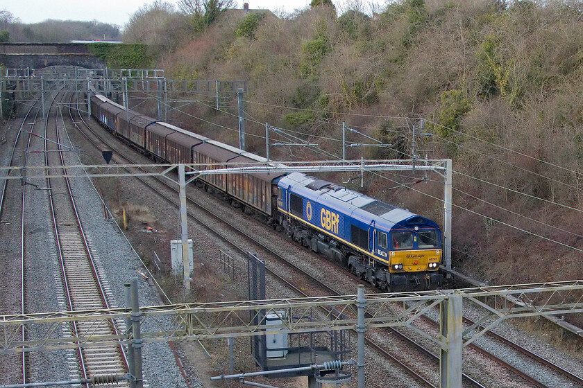 66797, 14.39 DIRFT-Dollands Moor (6O67, 2L), A508 bridge 
 The 14.39 DIRFT (Daventry) to Dollands Moor empty water train passes through Roade led by Beacon liveried and owned but GBRf operated 66797. It was worth the wait on a grey winter's afternoon as this was my first picture of this locomotive that was repatriated from Germany in 2021 where it had been operating as PB 513-09 / 266 036 since 2004. 
 Keywords: 66797 14.39 DIRFT-Dollands Moor 6O67 A508 bridge Beacon Rail GBRf