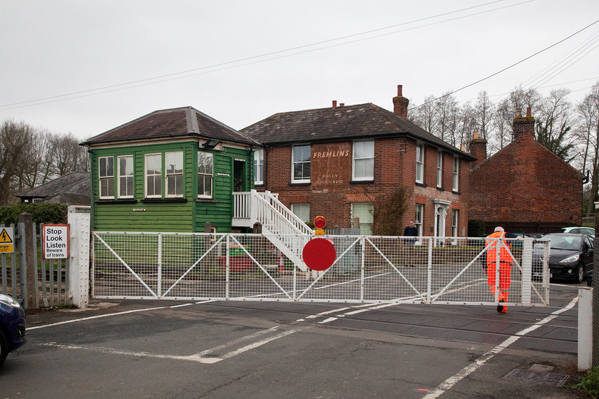 Opening the gates, Chartham level crossing 
 After a train has passed the crossing keeper opens the manual gates in Chartham village. No axle counters, laser control and CCTV here! The 1885 signal box, now reduced to a crossing box, received this unusual colour scheme in 1997. The replacement crossing gates themselves were installed in 2003. 
 Keywords: Chartham level crossing