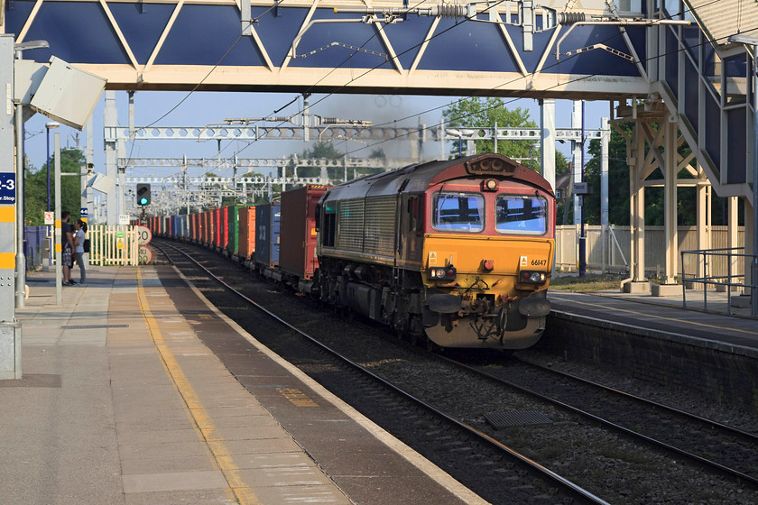 66147, 15.55 Southampton Western Docks-Birch Coppice (4M68), Tilehurst station 
 With the three other customers on Tilehurst station taking the only shelter from the searing afternoon sun that was available under the footbridge, 66147 works hard working the heavily laden and long 4M68 Freightliner. This working is the regular 15.55 Southampton Western Docks to Birch Coppice. 
 Keywords: 66147 15.55 Southampton Western Docks Birch Coppice 4M68 Tilehurst station