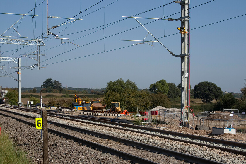 Future junction point, entry to Sergo Logistics Park, Milton Malsor 
 After the slow lines between Northampton and Hanslope Junction being completely closed for over a week I was expected to find some nice new shiny pointwork installed here at Milton Malsor to connect the Sergo Logistics Park to the network. Whilst this may have happened at the southern end to which access was not possible there is limited evidence of work here at the northern end. The marker post reads 62 miles and 44 chains and will be the official mileage of the junction once it is installed here with Freightliner and intermodal trains entering and leaving the Logistics Park. Notice the two buildings on the skyline, to the right is the Danes Camp leisure centre and to the left is the unusual spire of St Benedict's Church high up on Hunsbury Hill. 
 Keywords: Future junction point entry to Sergo Logistics Park Milton Malsor