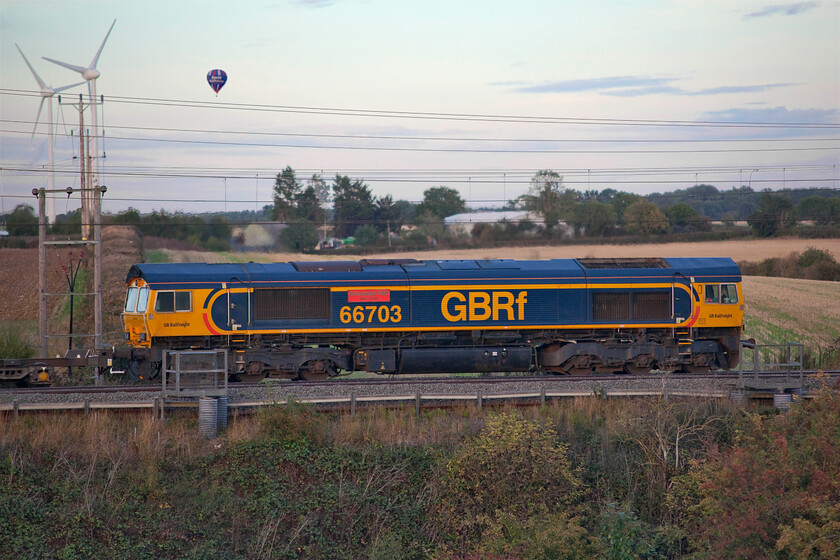 66703, 14.18 Trafford Park-Felixstowe (4L18, 2L), Roade hill 
 What a difference a few minutes makes at this location between the Northamptonshire villages of Roade and Ashton! Having captured the LSL 1Z41 charter in full sunshine a sort time earlier an errant cloud has spoilt the show as 4L18 (14.18 Trafford Park to Felixstowe) passes led by 66703 'Doncaster PSB 1981-2002'. Being early autumn the light is beginning to fade earlier in the evening and with the sun low in the sky a rather disappointing image has resulted improved in part by the appearance of a rather low-flying hot air balloon that looks, from this angle at least, perilously close to the sails of the M1 windfarm. 
 Keywords: Doncaster PSB 1981-2002