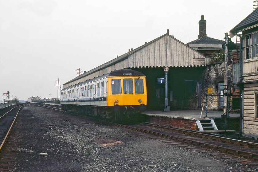 Class 114 DMU, 13.09 Cleethorpes-New Holland Pier, New Holland Town station 
 Having arrived at New Holland Town station a refurbished Class 114 DMU pauses working the 13.09 Cleethorpes to New Holland Pier service. Its destination is seen in the distance at the far end of the pier a fair way out into the Humber estuary. The archaic nature of the station is seen clearly in this view with old signage and a general tatty look. Also, notice how low the platform is compared to the train necessitating a small number of wooden steps along the platform to permit easier access for passengers. 
 Keywords: Class 114 DMU 13.09 Cleethorpes-New Holland Pier New Holland Town station First Generation DMU