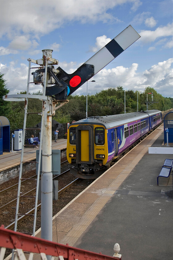 156475, NT 10.22 Newcastle-Carlisle, Prudhoe station 
 156475 stands at Prudhoe station waiting to leave with the 10.22 Newcastle to Carlisle service. It is about to pass under the wrought iron footbridge a number of which can be found at stations on the Tyne Valley route all built to the same basic design. It was notable how much the signal mast shook from side to side when the arm was pulled off and when being returned to danger; a little disconcerting for any passengers in such close proximity climbing or descending the footbridge steps! 
 Keywords: 156475 10.22 Newcastle-Carlisle Prudhoe station Northern