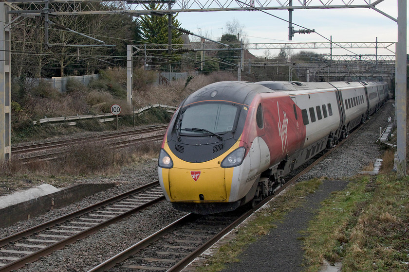 390050, VT 12.20 London Euston-Manchester Piccadilly (1H24, 24L), site of Castlethorpe station 
 The new flowing silk livery has certainly given the Pendolinos a major mid-life facelift and it makes them much mores easy to photograph on a dull day such as this at Castlethorpe. 390050 passes the remains of the village's station platforms with the 12.20 Euston to Manchester Piccadilly. Again, something went wrong as the service arrived 24 minutes late with the delays occurring in the vicinity of Tamworth and Rugeley. 
 Keywords: 390050 12.20 London Euston-Manchester Piccadilly 1H24 site of Castlethorpe station