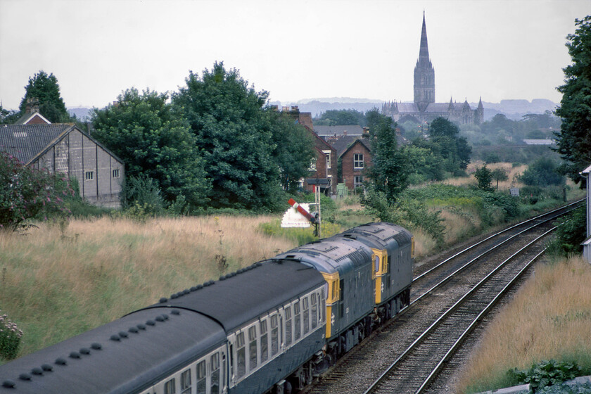 33015 & 33043, 13.40 Exeter St. David's-Brighton (1O86), Skew bridge Bemerton 
 With the grand four hundred and four feet tall spire of Salisbury cathedral dominating this view looking south-east from Bemerton's Skew bridge the 13.40 Exeter St. David's to London Waterloo passes underneath. I saw and photographed 33015 and 33043 earlier in the day working west, see... https://www.ontheupfast.com/p/21936chg/30035687469/x33015-33043-09-20-brighton-exeter. Notice the Salisbury West home signal complete with its sighting board. The overgrown area to the left of the train was, until 1973, occupied by the GWR independent double track route that diverged away from the L&SWR lines at Wilton a short distance behind where I am standing. 
 Keywords: 33015 33043 13.40 Exeter St. David's-Brighton 1O86 Skew bridge Bemerton Crompton