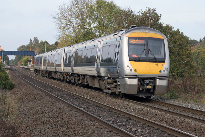 168113, CH 12.55 Birmingham Moor Street-London Marylebone (1H45, RT), Widney Manor station 
 168113 has just passed through Widney Manor station located just to the south of Solihull. The Chiltern service left Birmingham Moor Street at 12.55 working through to London Marylebone as 1H45. I am standing at the far end of Widney Manor's station car park leaning over the fence. As can be seen, the earlier clear blue skies have now been covered with a veil of grey but some of the sun's rays are still penertraiting adding a little extra light to the image. 
 Keywords: 168113 12.55 Birmingham Moor Street-London Marylebone 1H45 Widney Manor station