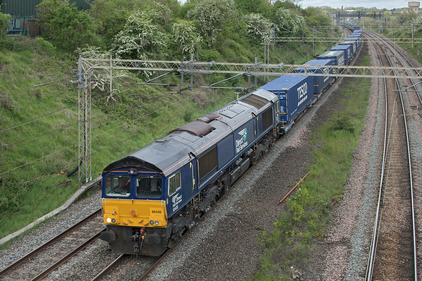 66430, 10.51 DIRFT-Ripple Lane (4L98, RT), Victoria bridge 
 Having first headed north from Daventry's rail freight terminal as far as Rugby it is now seen heading in the right direction again working the 4L98 Tesco Express to Purfleet. The reason for this odd move was the closure of the slow lines south of Northampton so it was forced to take the 'fast' Weedon route. With DRS' 66430 leading the train it is seen sweeping around the reverse curves just south of Roade identified by the water tower in the top right of the photograph. 
 Keywords: 66430 10.51 DIRFT-Ripple Lane 4L98 Victoria bridge Tesco Express DRS