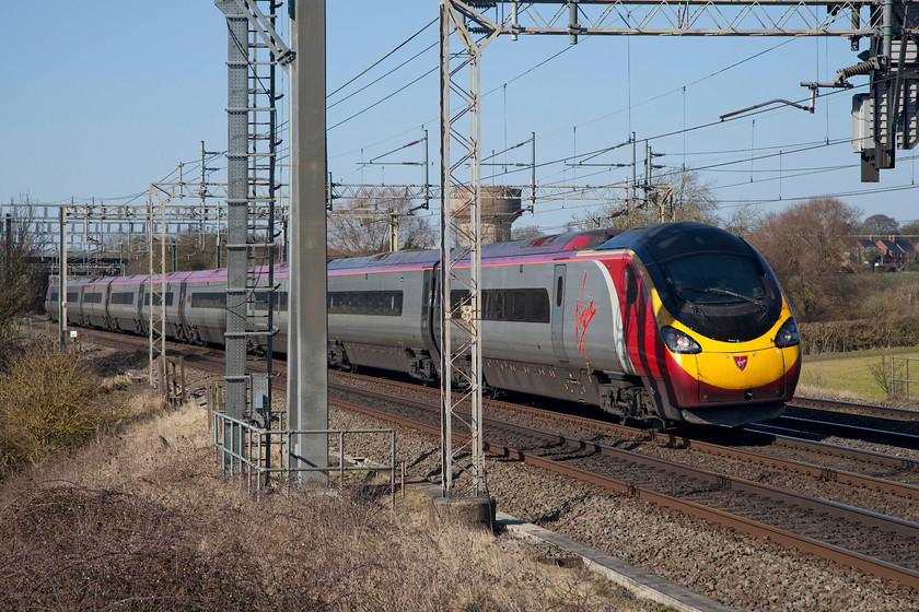 390042, VT 12.30-Birmingham New Street-London Euston (1B21, 12L), Roade Hill 
 Having got the green light from the signal contained in the over-sized gantry above it, 390042 gets under way again from Roade Hill near Northampton with the 12.30 Birmingham New Street to London Euston where it arrived some 12 minutes late. Delays were improving by this stage caused by problems in the Milton Keynes area. 
 Keywords: 390042 1B21 12L Roade Hill