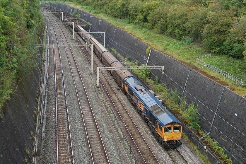 66757, 14.39 DIRFT-Dollands Moor (6O67, 10L), Roade cutting 
 The seven-day-a-week 6O67 empty 'bottled water train' passes through Roade cutting led by 66757 'West Somerset Railway'. This and the balancing 6M45 fully loaded train are probably the most regular freight trains that pass along this section of the WCML. 
 Keywords: 66757 14.39 DIRFT-Dollands Moor 6O67 Roade cutting GBRf West Somerset Railway