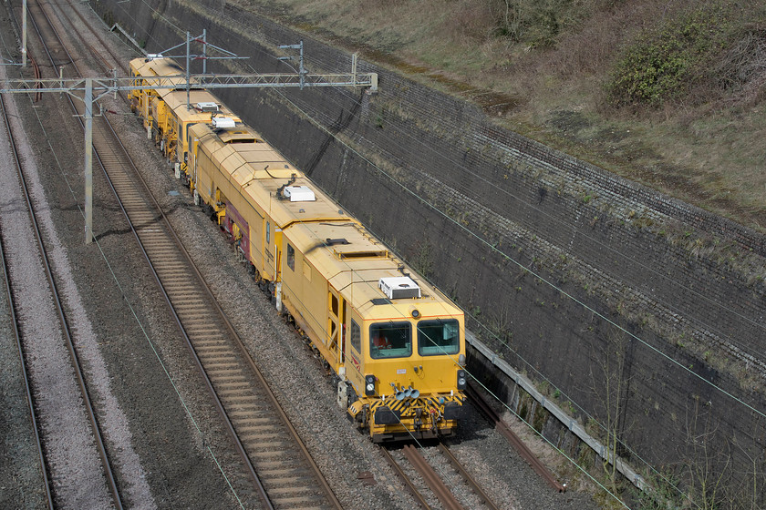 DR73116 & DR77906, 06.25 Parkeston-Watford London Concrete, Roade Cutting 
 Two track machines, DR73116 and DR77906 pass through Roade cutting at a rather sedate speed. They are in the final stage of their rather convoluted journey that started out early from Parkeston near Harwich. They then travelled via Ipswich, Cambridge, Peterborough, Leicester, Nuneaton and then down the WCML to Watford. 
 Keywords: DR73116 DR77906 06.25 Parkeston-Watford London Concrete Roade Cutting