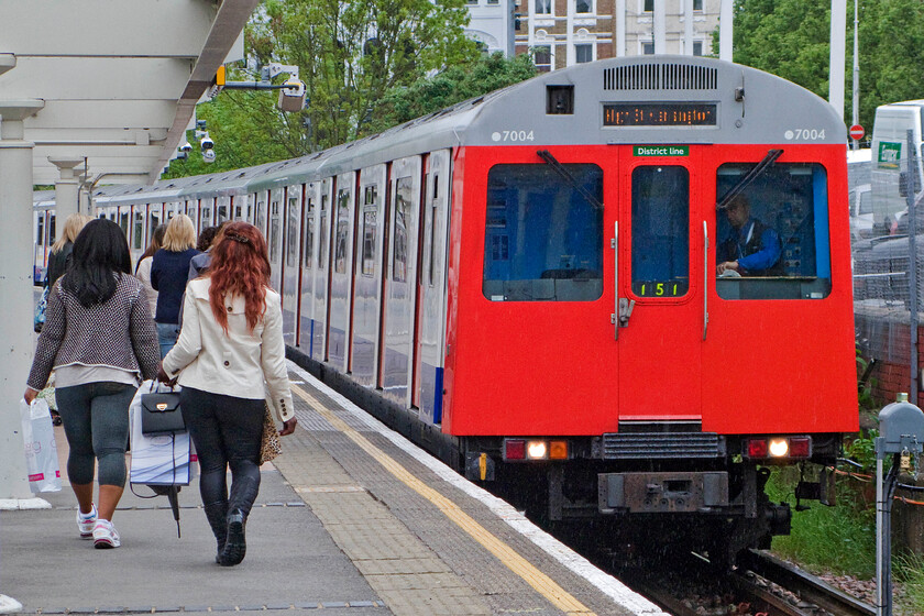 7004, LU Kensington High Street-Kensington Olympia District Line shuttle, Kensington Olympia station 
 Having enjoyed their day at a show inside Kensington Olympia passengers make their way down the platform to join D-Stock 7004 for the District Line shuttle back to High Street Kensington. The D-Stock has been in operation since the very early 1980s but they are due for replacement in the near future. 
 Keywords: 7004 Kensington High Street-Kensington Olympia District Line shuttle Kensington Olympia station