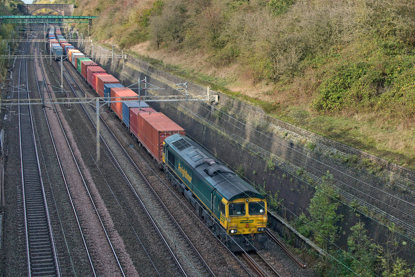 66596, 12.12 Lawley Street-London Gateway (4L96), Roade cutting 
 Freight two....
As the 4M88 freight disappears from view in Roade cutting, 66596 leads the 12.12 Lawley Street to London Gateway Freightliner in the other direction. If 66596 had not been leading the up Freightliner so slowly, that I would estimate at about forty mph, then the two trains would have passed to the south or even level with me. Notice the unsightly rust stains from the windscreen surrounds. This problem seems to be one that problem afflicts class 66s. 
 Keywords: 66596 12.12 Lawley Street-London Gateway 4L96 Roade cutting