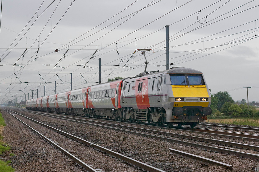 91102, GR 08.06 London King`s Cross-Leeds (1D05), Holme Green crossing TL192426 
 91102 'City of York' speeds across the flatlands of Bedfordshire leading the 08.06 King's Cross to Leeds morning express. These locomotives are incredibly powerful and have really left their mark on the ECML since their introduction in 1989, see....... https://www.youtube.com/watch?v=wiDQkZzOevI Notice the jaunty angle of the electricity post in the field to the right of the train! 
 Keywords: 91102 08.06 London King`s Cross-Leeds 1D05 Holme Green crossing TL192426Virgin East Coast IC225 City of York