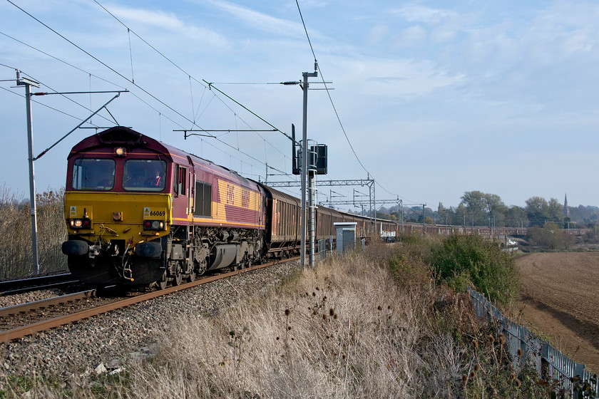 66069, 09.27 Dollands Moor-DIRFT (6M45), Wilsons Crossing 
 The daily and regular as clockwork 6M45 'bottled water train' takes the rising gradient out of Northampton past Wilson's Crossing. This working is the 09.27 Dollands Moor to Daventry railfreight terminal that is only a short distance away from this spot. After a miserable start to the day, the sun had come out and it was a pleasantly warm early November afternoon. 
 Keywords: 66069 09.27 Dollands Moor-DIRFT 6M45 Wilsons Crossing