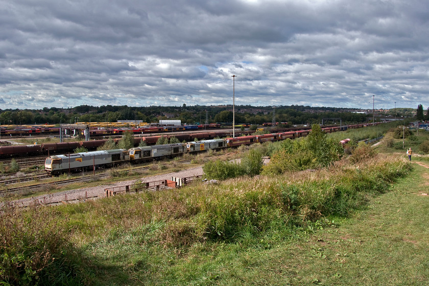 Andy & 60067, 60032, 60088, 60003, 60058 & 60051, stored, Toton yard 
 Just as Andy and I were going to return to the car for the journey home, the sun burst out through a hole in the cloud so we both retrained our cameras on the glorious scene above Toton Yard! I have gone for an ultra wide-angled image that includes Andy off to the far right. The line of stored Class 60s in the foreground are (as far as I could get)....60067 'James Clerk-Maxwell', 60032 'William Booth', 60088 'Buachaille Etive Mor', 60003 'Freight Transport Association' (still wearing a sort of homemade nameplate), 60058 'John Howard' and 60051 'Mary Somerville'. I suspect that if or when Andy and I next visit the famous bank that the line of Class 60s will have gone and been unceremoniously cut up but I expect we said that when we last visited back in 2010! 
 Keywords: Andy 60067 James Clerk-Maxwell 60032 William Booth 60088 Buachaille Etive Mor 60003 Freight Transport Association 60058 John Howard 60051 Mary Somerville stored Toton yard.